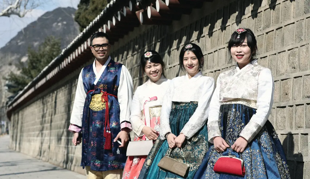 Travellers in hanbok along a palace wall in Seoul